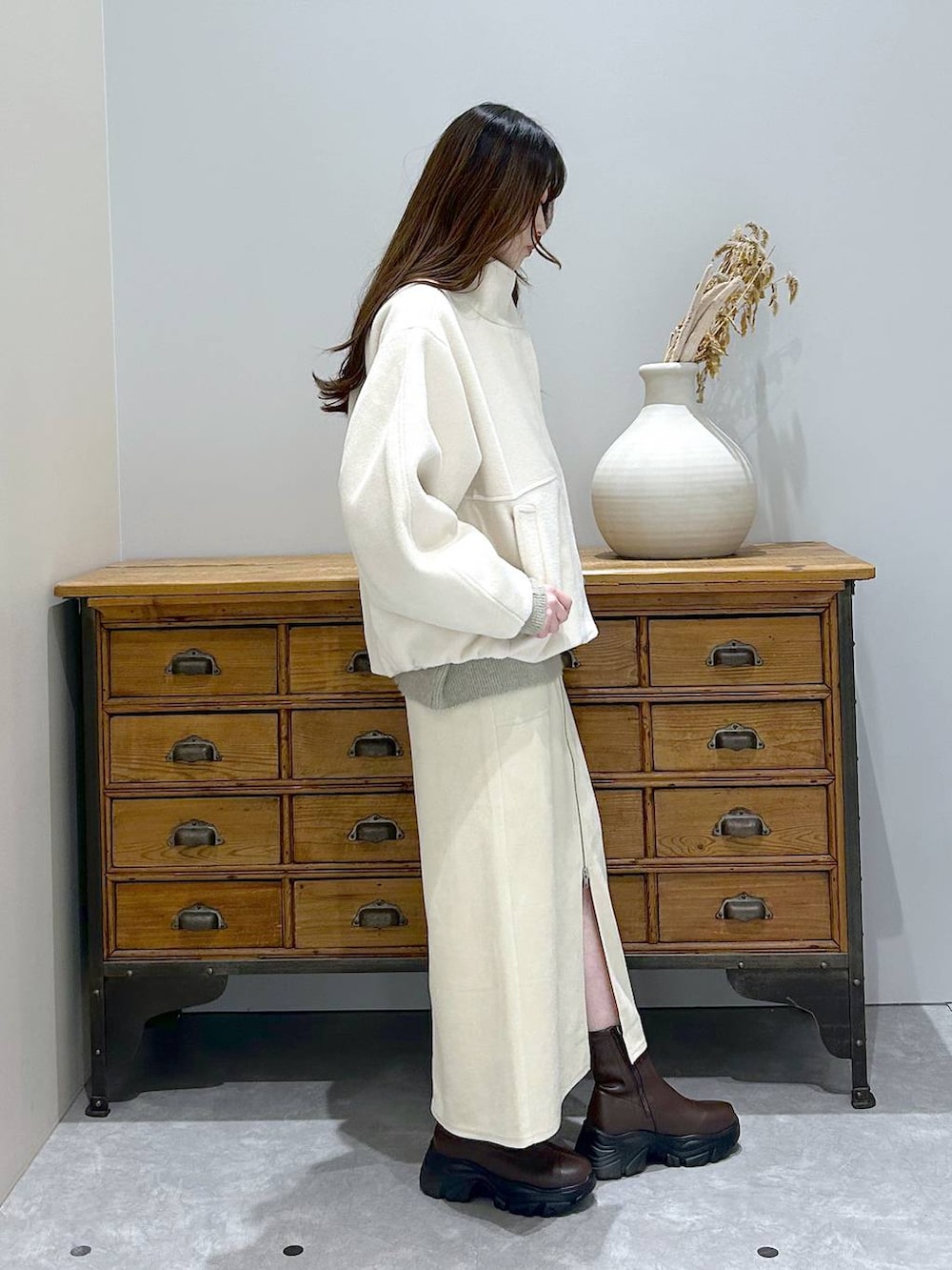 ブラウン系のブーツ、ホワイト系のスカート、ホワイト系のブルゾンを着用したレディースの冬コーディネートの3枚目の写真