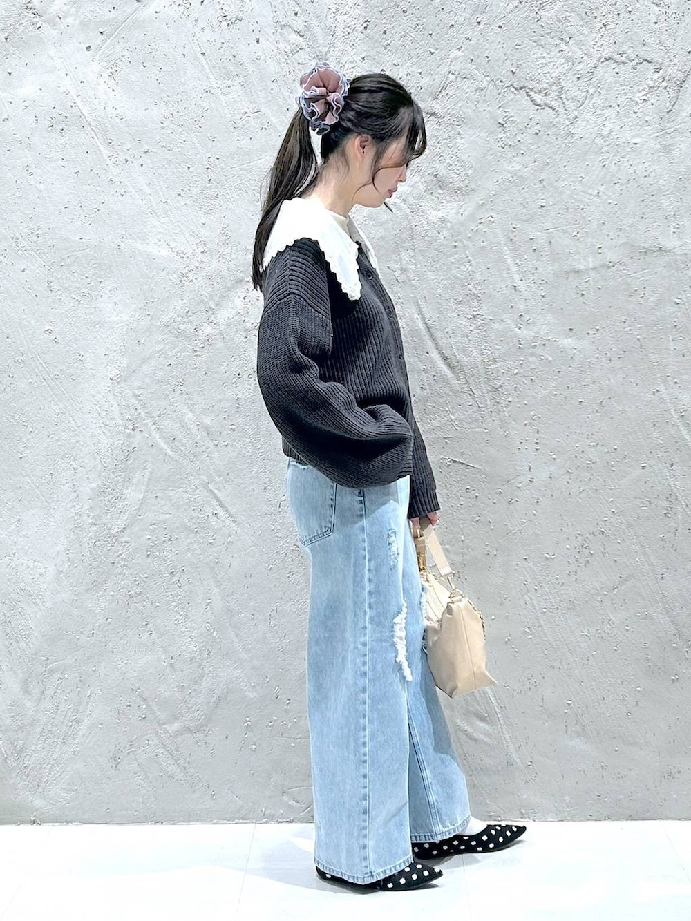 ブルー系のデニムパンツ、ベージュ系のショルダーバッグ、ホワイト系のTシャツ/カットソーを着用したレディースの冬コーディネートの2枚目の写真