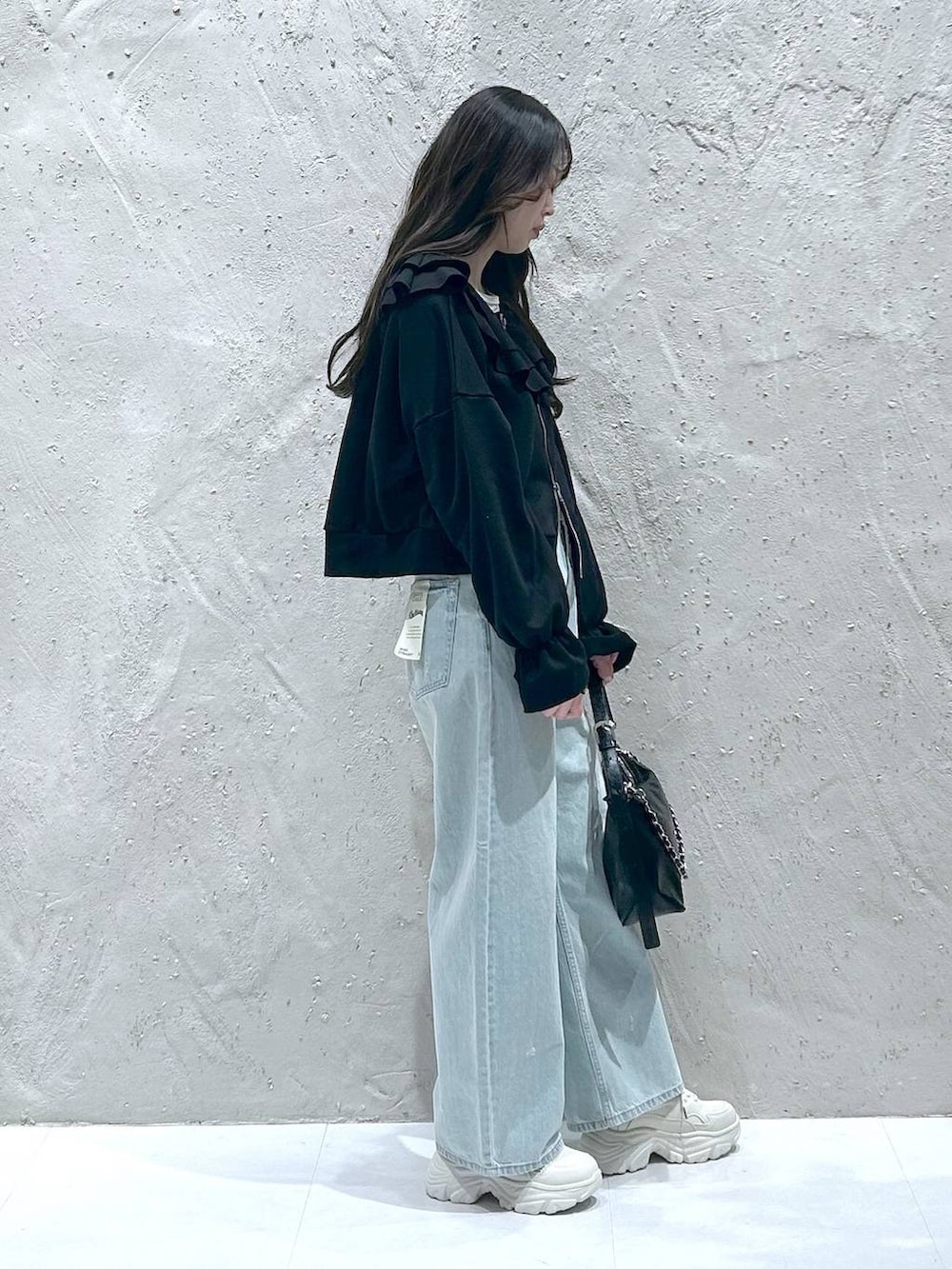 ブルー系のデニムパンツ、ブラック系のショルダーバッグ、ブラック系のスウェットを着用したレディースの冬コーディネートの2枚目の写真