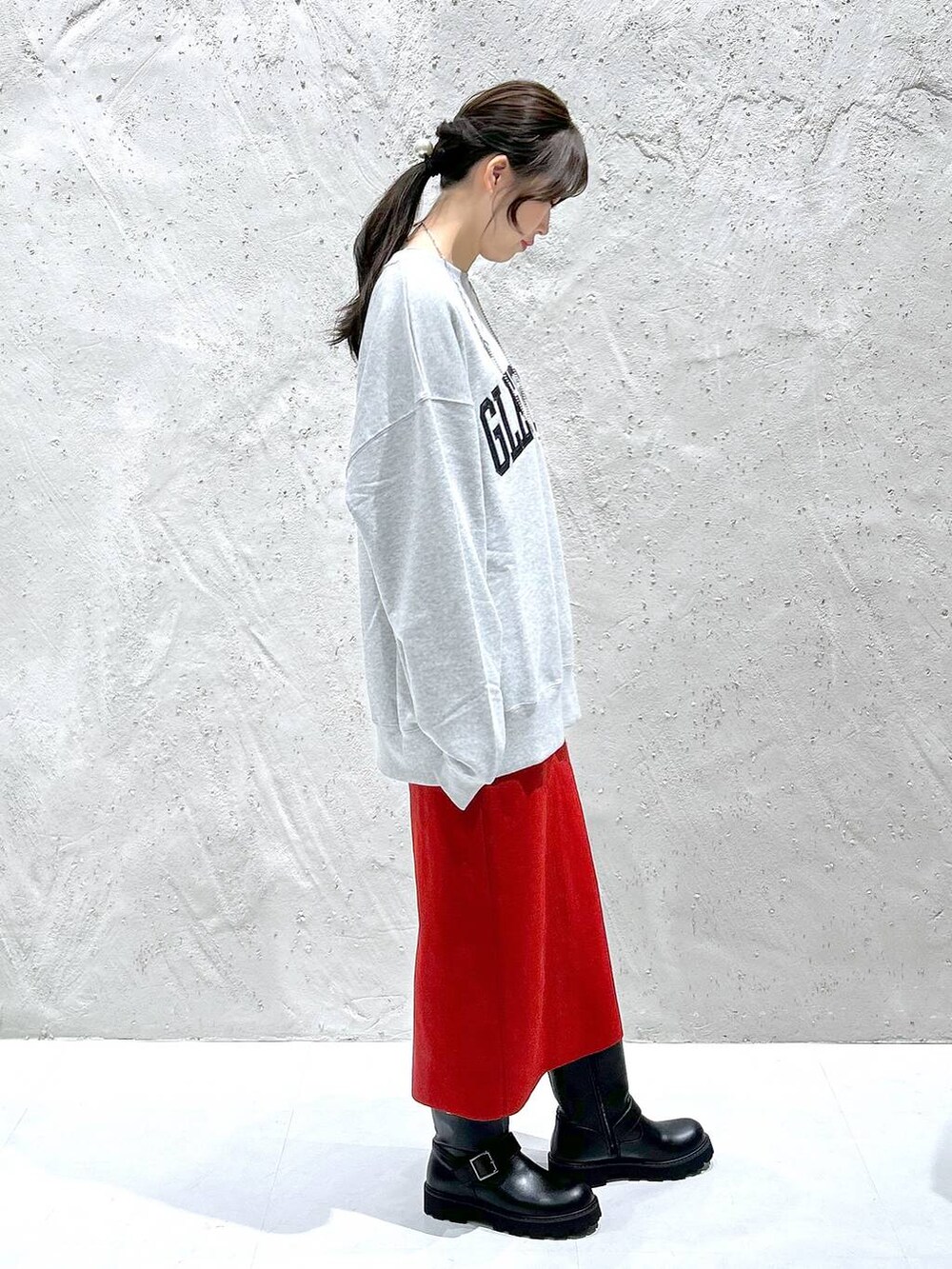 レッド系のスカート、ブラック系のブーツ、グレー系のスウェットを着用したレディースの秋コーディネートの3枚目の写真