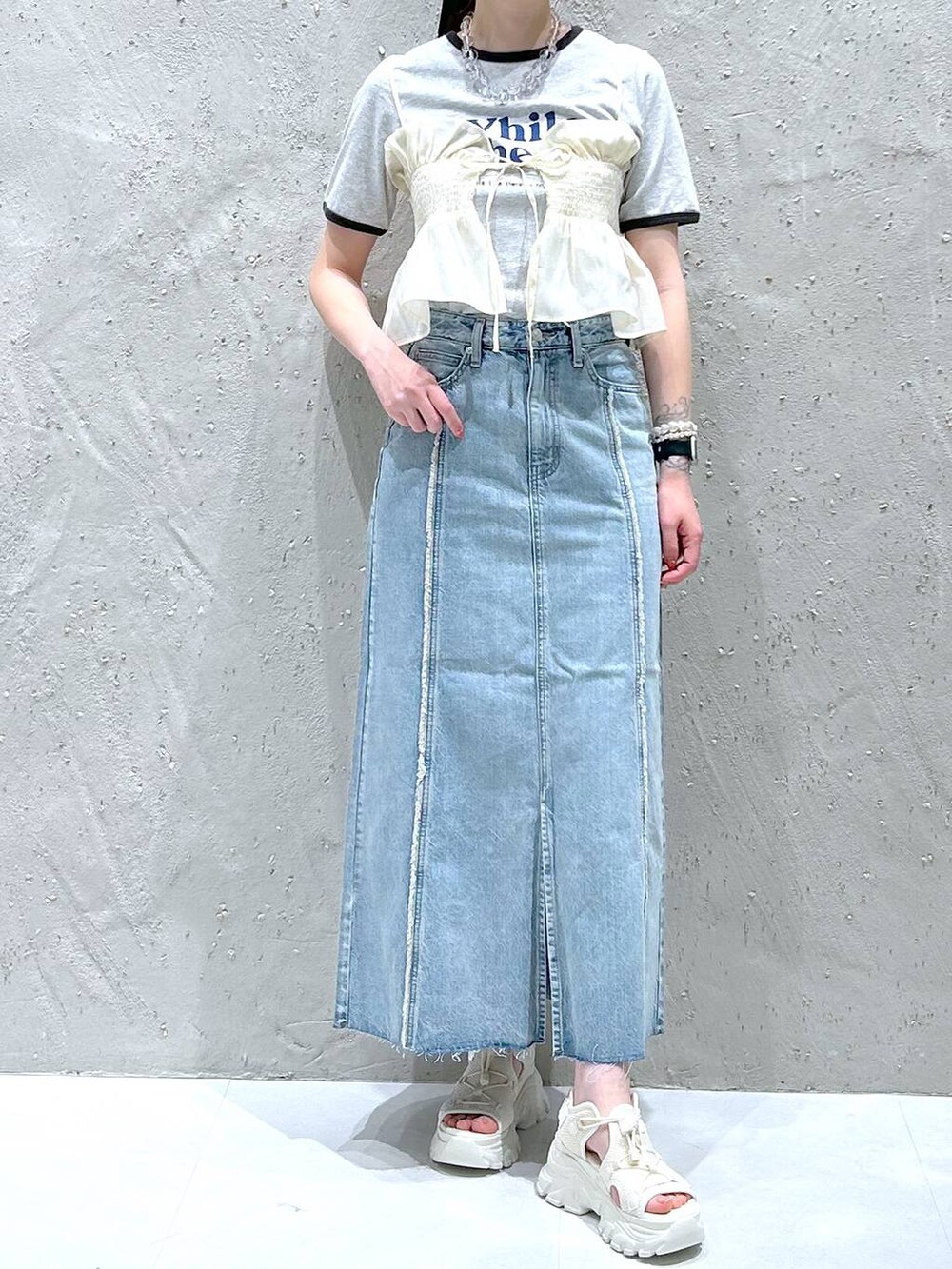 ブラック系のサンダル、グレー系のTシャツ/カットソー、ブルー系のスカートを着用したレディースの春コーディネートの2枚目の写真
