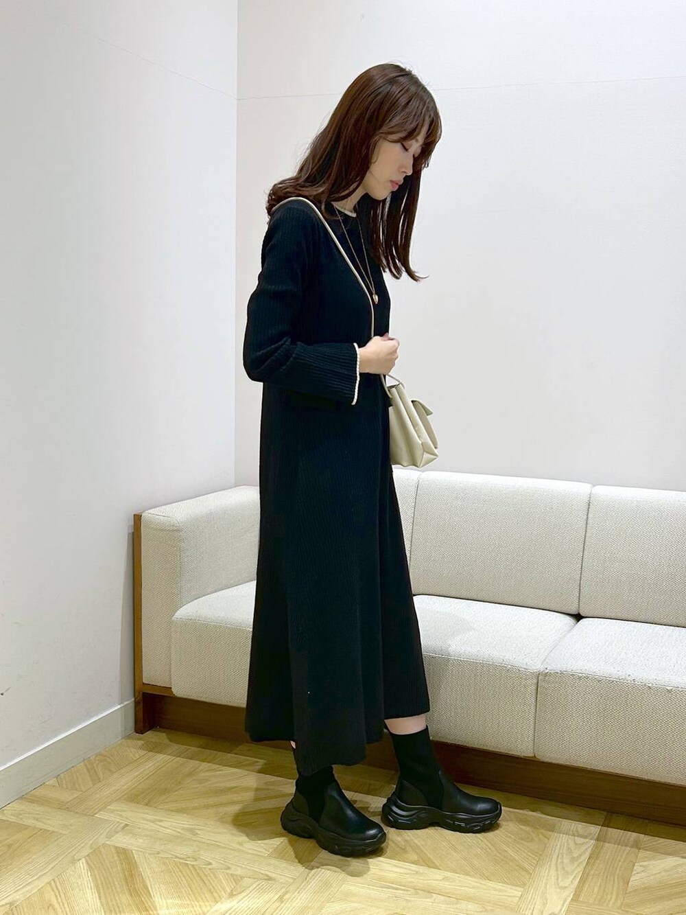 ホワイト系のショルダーバッグ、ブラック系のワンピース、ブラック系のブーツを着用したレディースの秋コーディネートの3枚目の写真