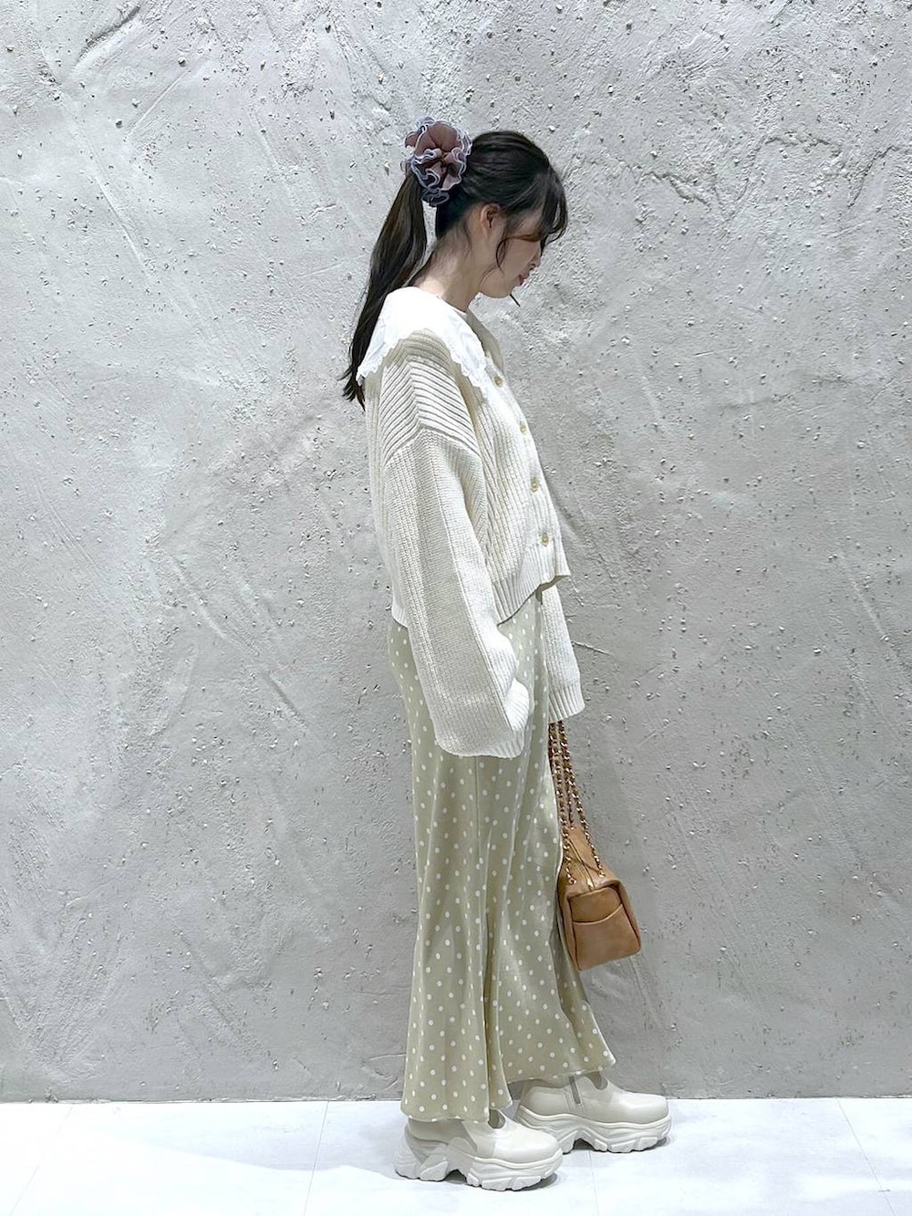 ホワイト系のブーツ、ベージュ系のスカート、ブラック系のショルダーバッグを着用したレディースの冬コーディネートの2枚目の写真