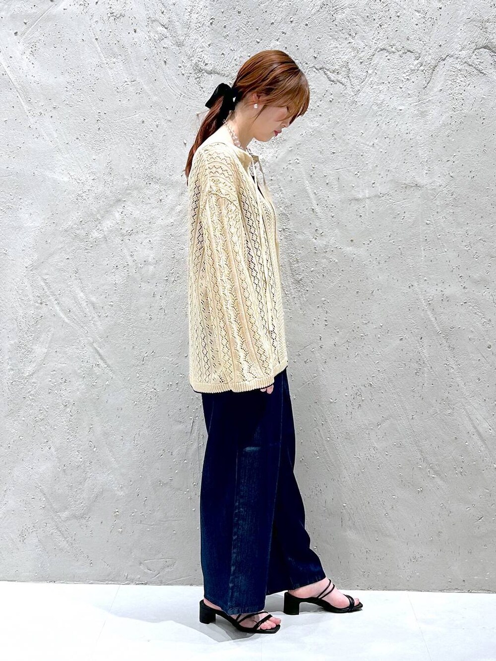 ホワイト系のニット/セーター、ブルー系のデニムパンツ、ブラック系のタンクトップを着用したレディースの春コーディネートの3枚目の写真