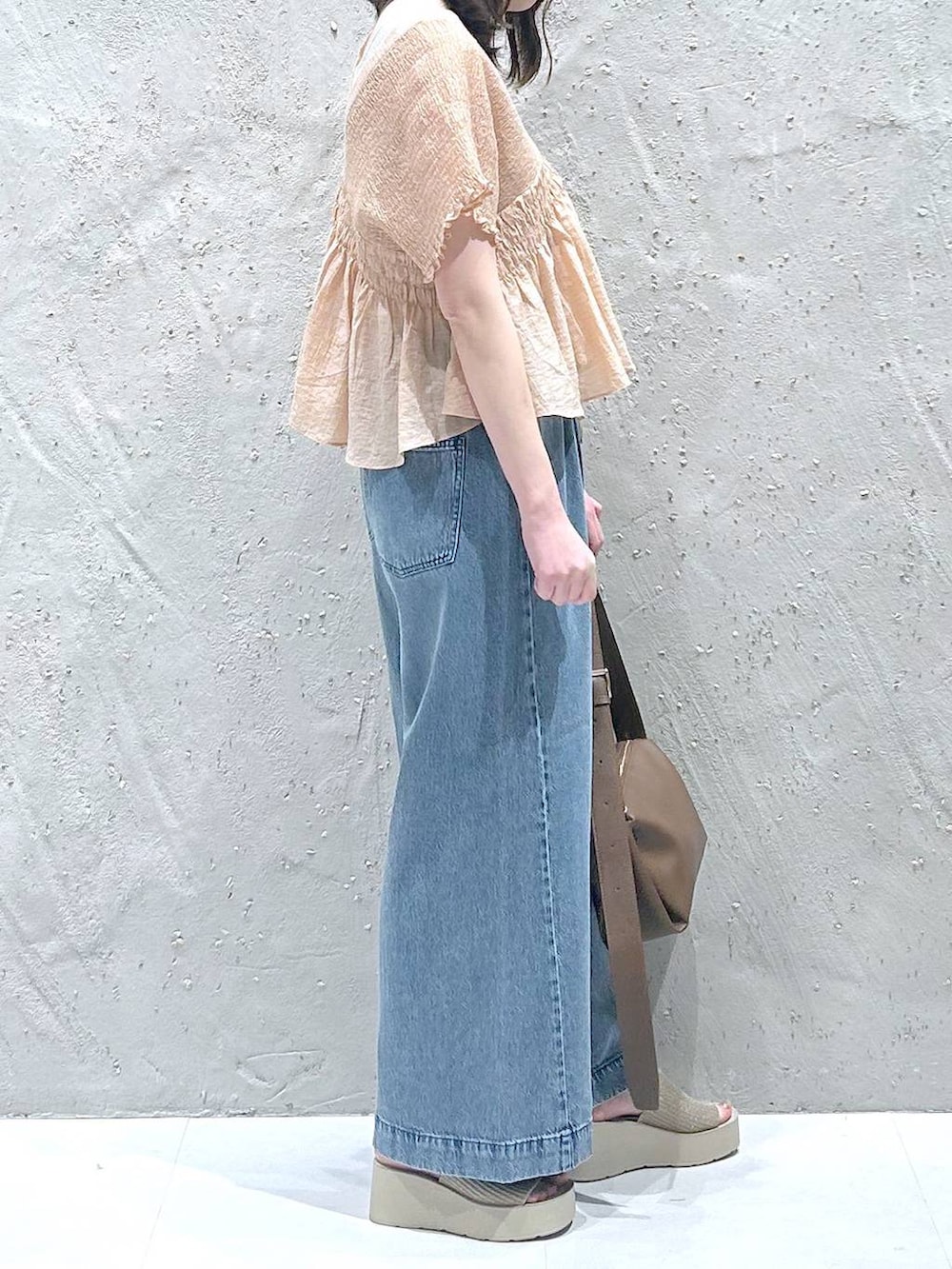 ブルー系のデニムパンツ、ホワイト系のサンダル、ブラウン系のショルダーバッグを着用したレディースの夏コーディネートの4枚目の写真
