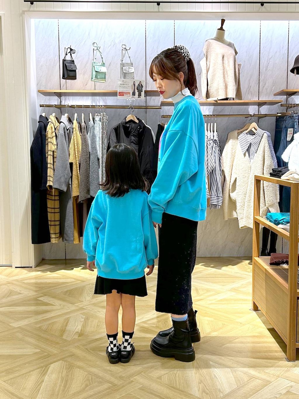 ホワイト系のTシャツ/カットソー、ブラック系のブーツ、ブラック系のスカートを着用したレディースの秋コーディネートの2枚目の写真