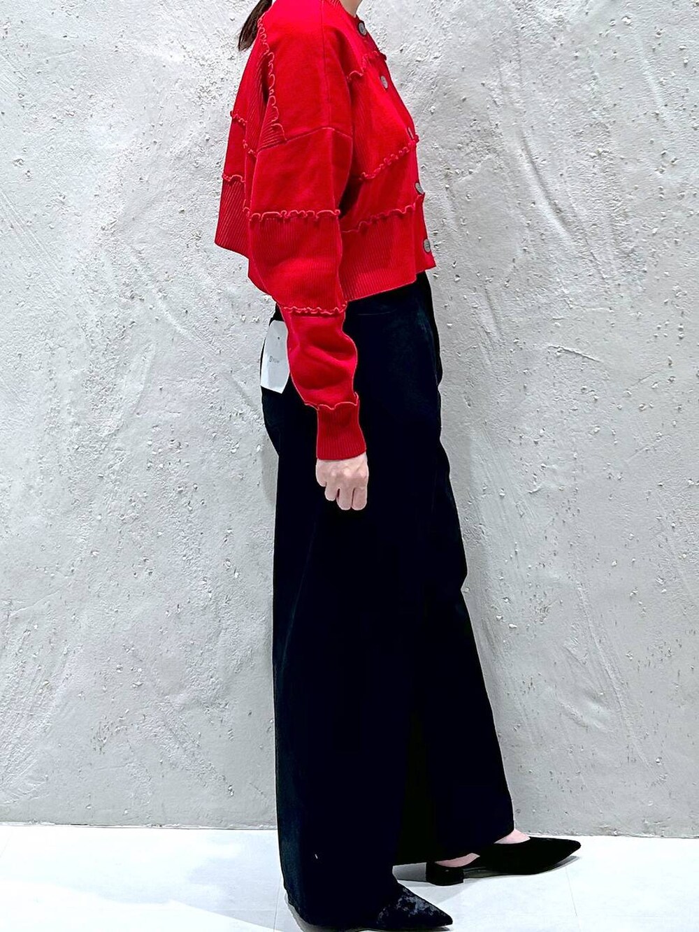 ブラック系のデニムパンツ、ブラック系のパンプス、レッド系のニット/セーターを着用したレディースの秋コーディネートの4枚目の写真