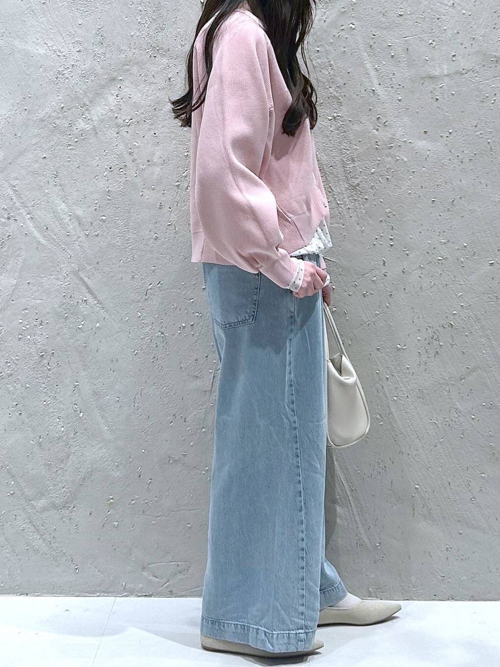 ホワイト系のショルダーバッグ、ブルー系のデニムパンツ、ホワイト系のパンプスを着用したレディースの春コーディネートの4枚目の写真