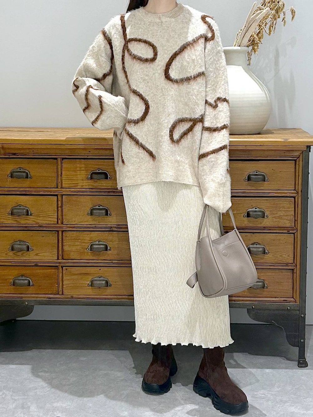 ブラウン系のブーツ、グレー系のショルダーバッグ、ホワイト系のスカートを着用したレディースの秋コーディネートの4枚目の写真