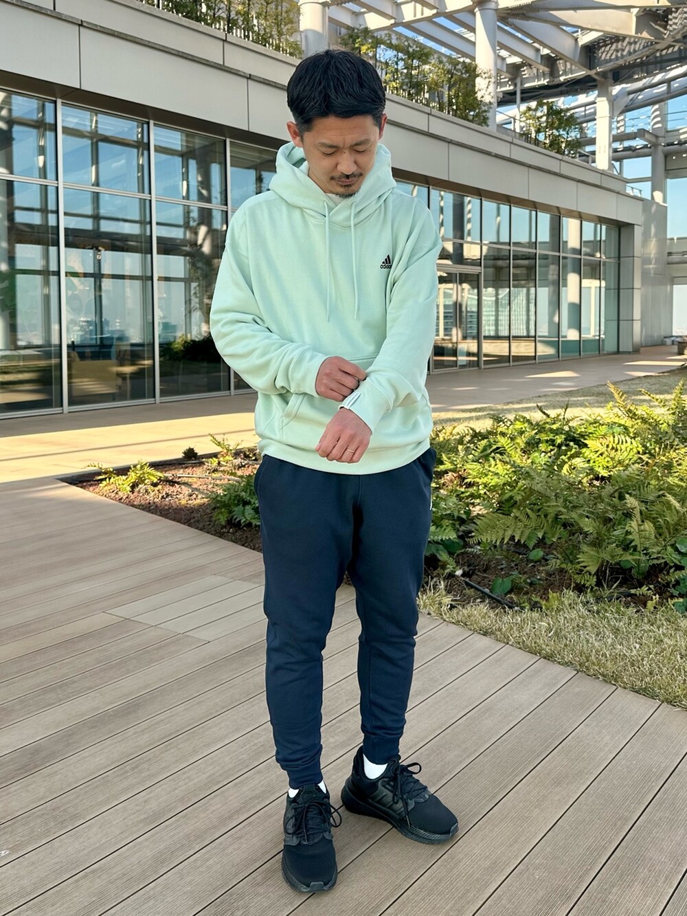 グリーン系のパーカー、ブルー系のスウェットパンツ、ブラック系のスニーカーを着用したメンズの冬コーディネートの2枚目の写真