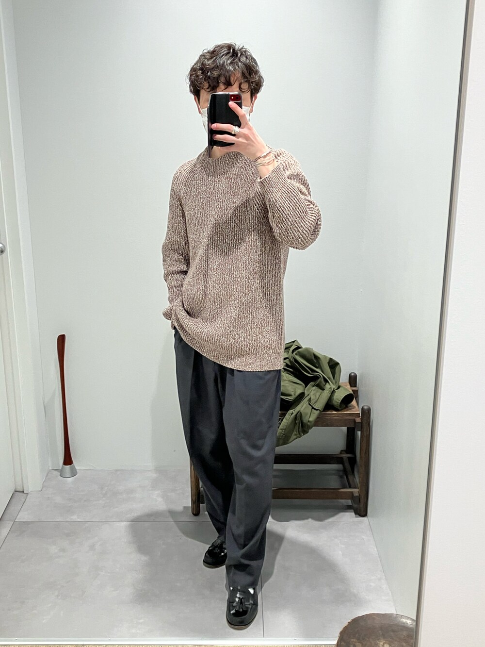 グリーン系のミリタリージャケット、ブラウン系のニット/セーター、グレー系のスラックスを着用したメンズの冬コーディネートの2枚目の写真