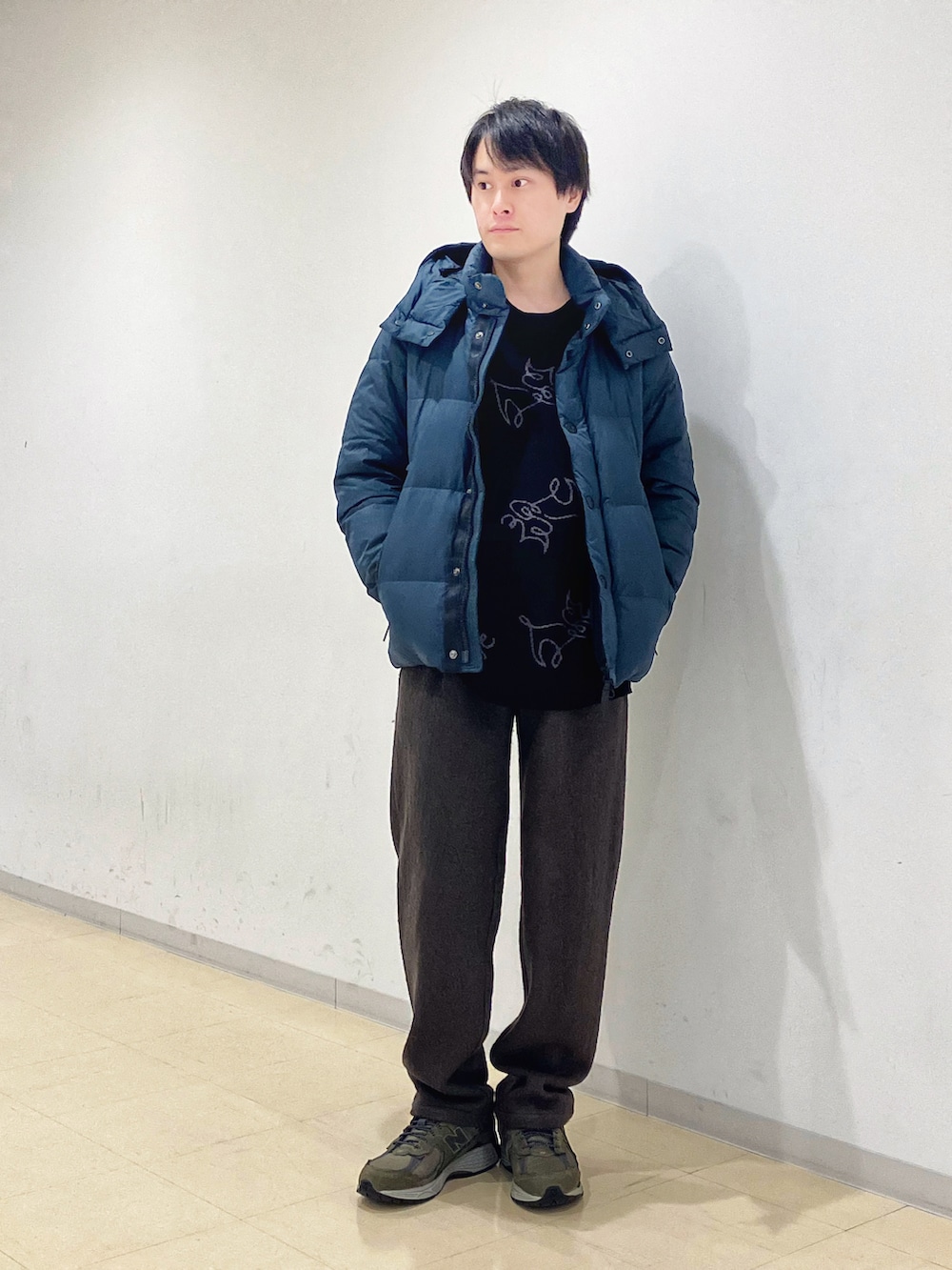 グリーン系のダウンジャケット/コート、ブラック系のニット/セーター、グリーン系のスラックスを着用したメンズの秋コーディネートの4枚目の写真