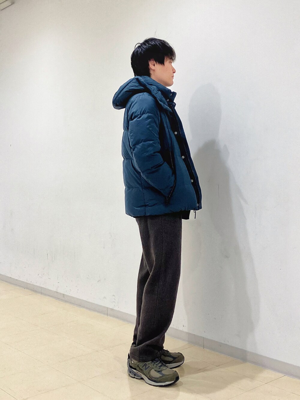 グリーン系のダウンジャケット/コート、ブラック系のニット/セーター、グリーン系のスラックスを着用したメンズの秋コーディネートの2枚目の写真