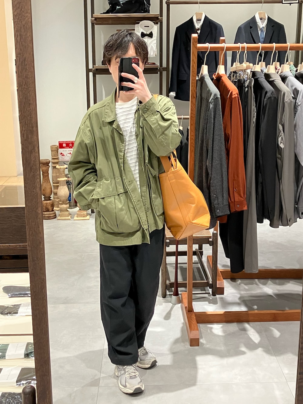 グリーン系のミリタリージャケット、ホワイト系のTシャツ/カットソー、ブラウン系のトートバッグを着用したメンズの春コーディネートの5枚目の写真