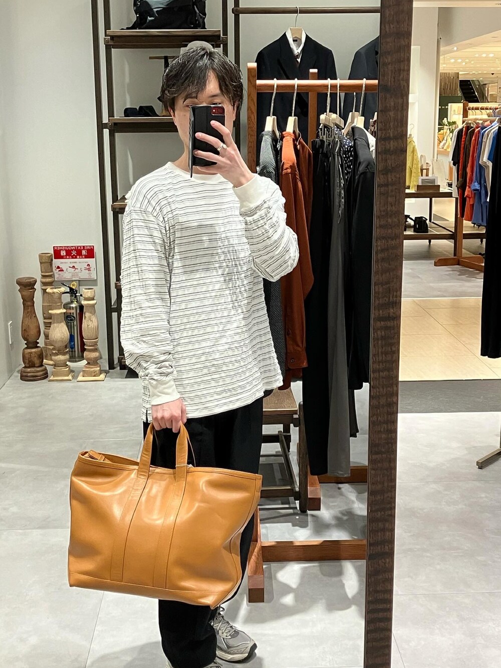 グリーン系のミリタリージャケット、ホワイト系のTシャツ/カットソー、ブラウン系のトートバッグを着用したメンズの春コーディネートの4枚目の写真