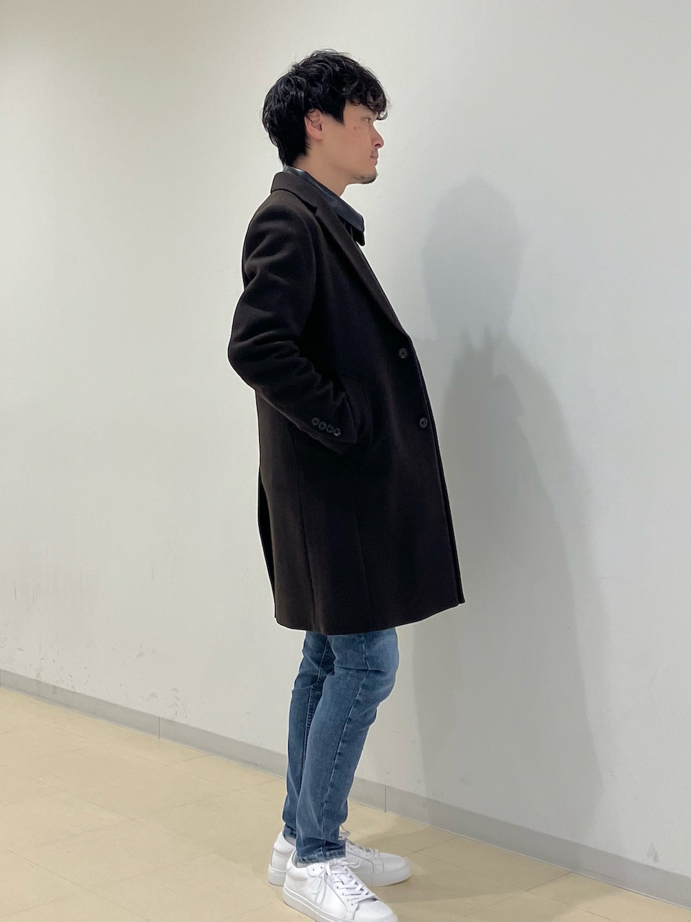 ブラウン系のチェスターコート、ブラック系のライダースジャケット、ブルー系のデニムパンツを着用したメンズの冬コーディネートの3枚目の写真