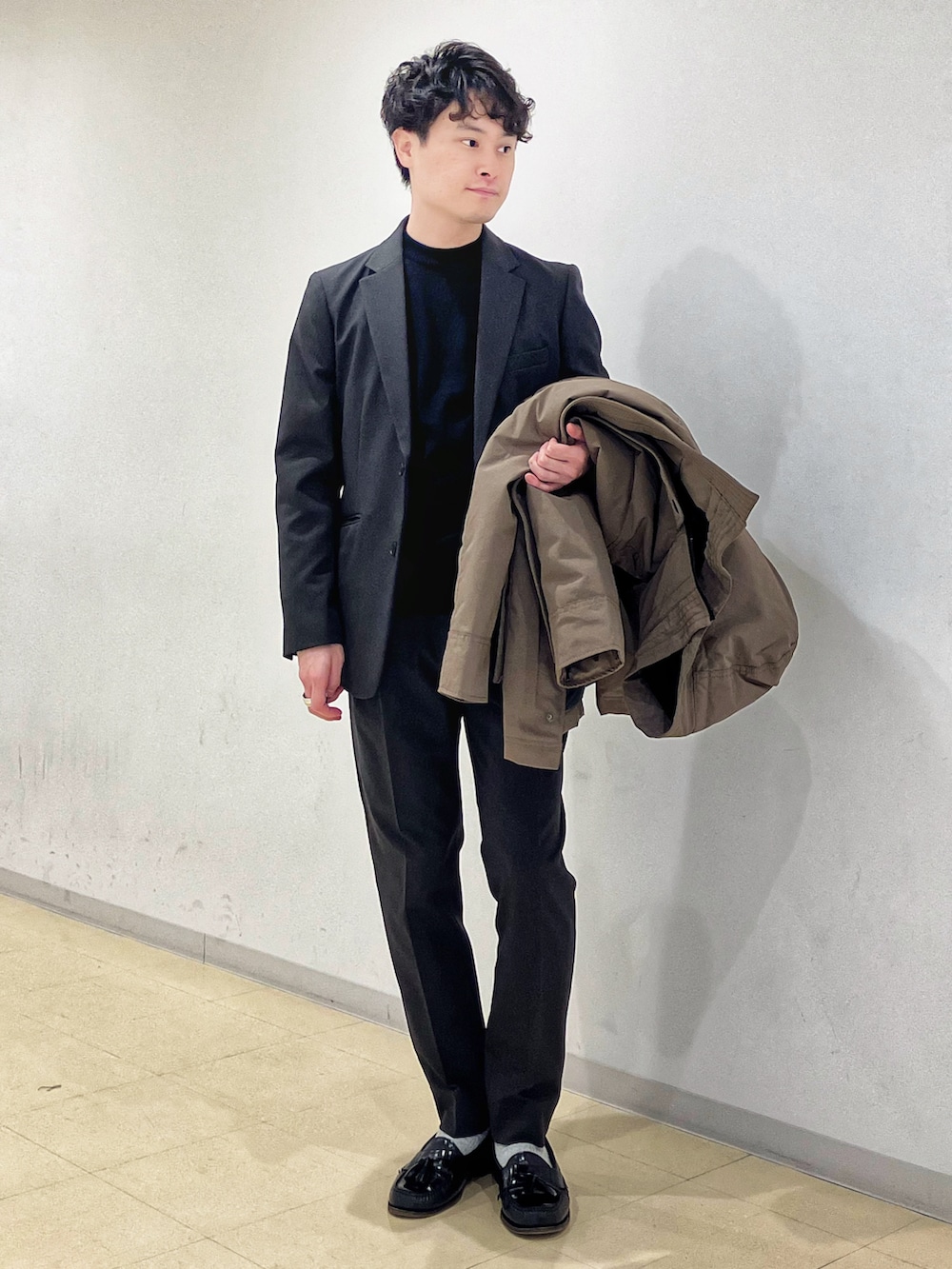 ブラウン系のダウンジャケット/コート、グレー系のセットアップ、ブラック系のニット/セーターを着用したメンズの冬コーディネートの3枚目の写真