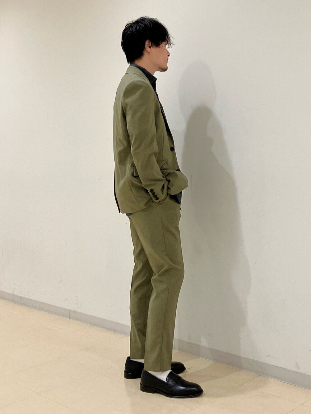 グリーン系のセットアップ、グレー系のシャツ/ブラウス、ブラック系のローファーを着用したメンズの夏コーディネートの2枚目の写真