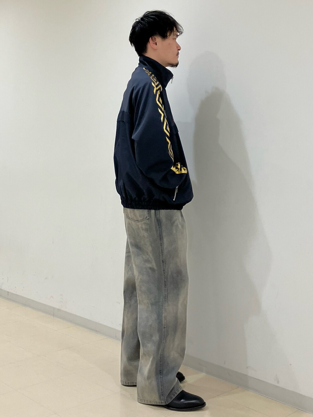 ブルー系のブルゾン、ブラック系のデニムパンツ、ブラック系のブーツを着用したメンズの春コーディネートの2枚目の写真