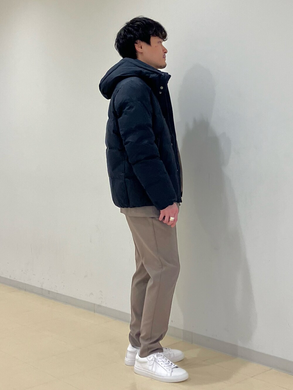 グレー系のニット/セーター、ブラック系のダウンジャケット/コート、ベージュ系のセットアップを着用したメンズの冬コーディネートの2枚目の写真