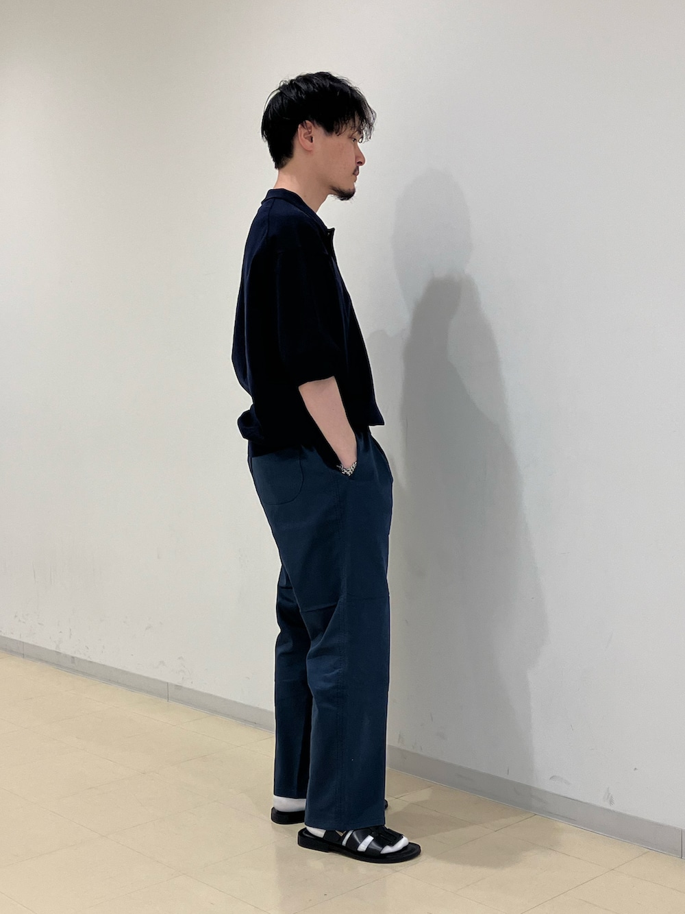 ブラック系のポロシャツ、ブルー系のその他パンツ、ブラック系のサンダルを着用したメンズの春コーディネートの2枚目の写真