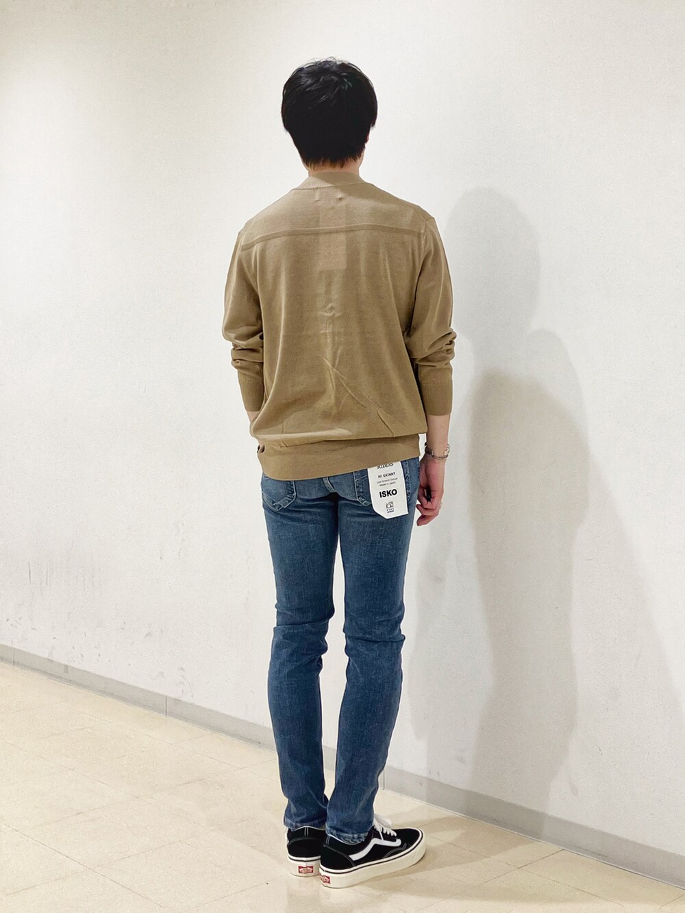 ベージュ系のニット/セーター、ブラック系のスニーカー、ブルー系のデニムパンツを着用したメンズの秋コーディネートの3枚目の写真