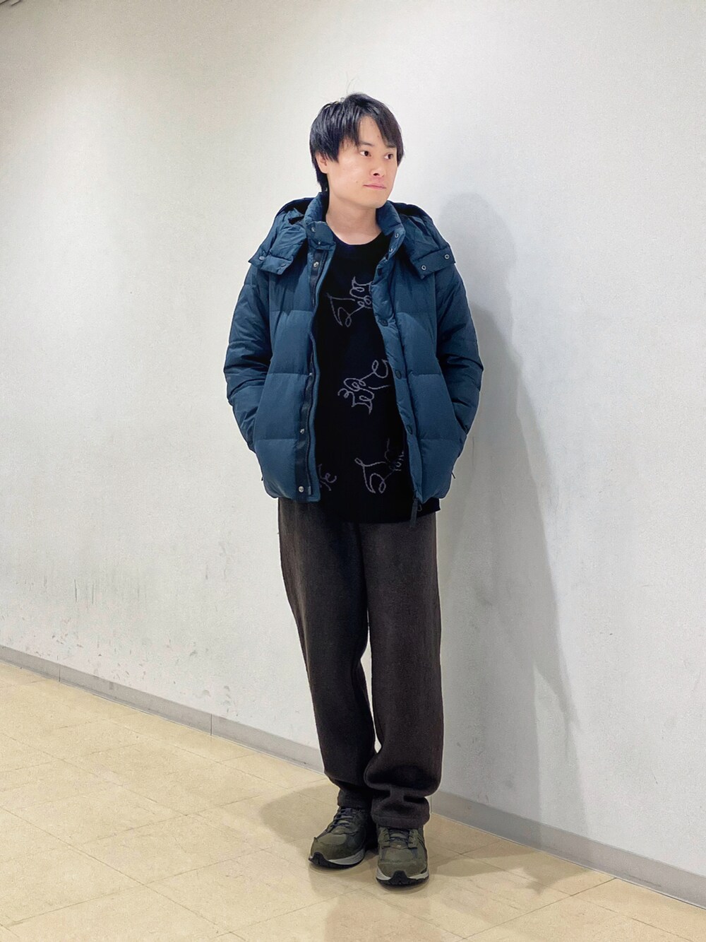 グリーン系のダウンジャケット/コート、ブラック系のニット/セーター、グリーン系のスラックスを着用したメンズの秋コーディネートの5枚目の写真