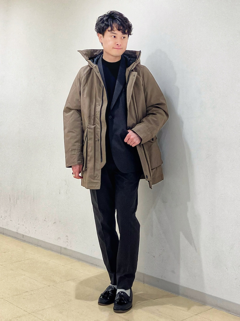 ブラウン系のダウンジャケット/コート、グレー系のセットアップ、ブラック系のニット/セーターを着用したメンズの冬コーディネートの2枚目の写真