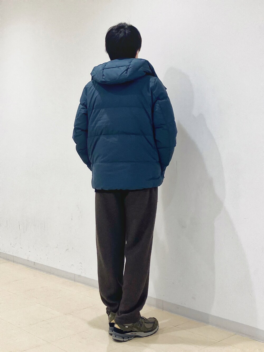 グリーン系のダウンジャケット/コート、ブラック系のニット/セーター、グリーン系のスラックスを着用したメンズの秋コーディネートの3枚目の写真