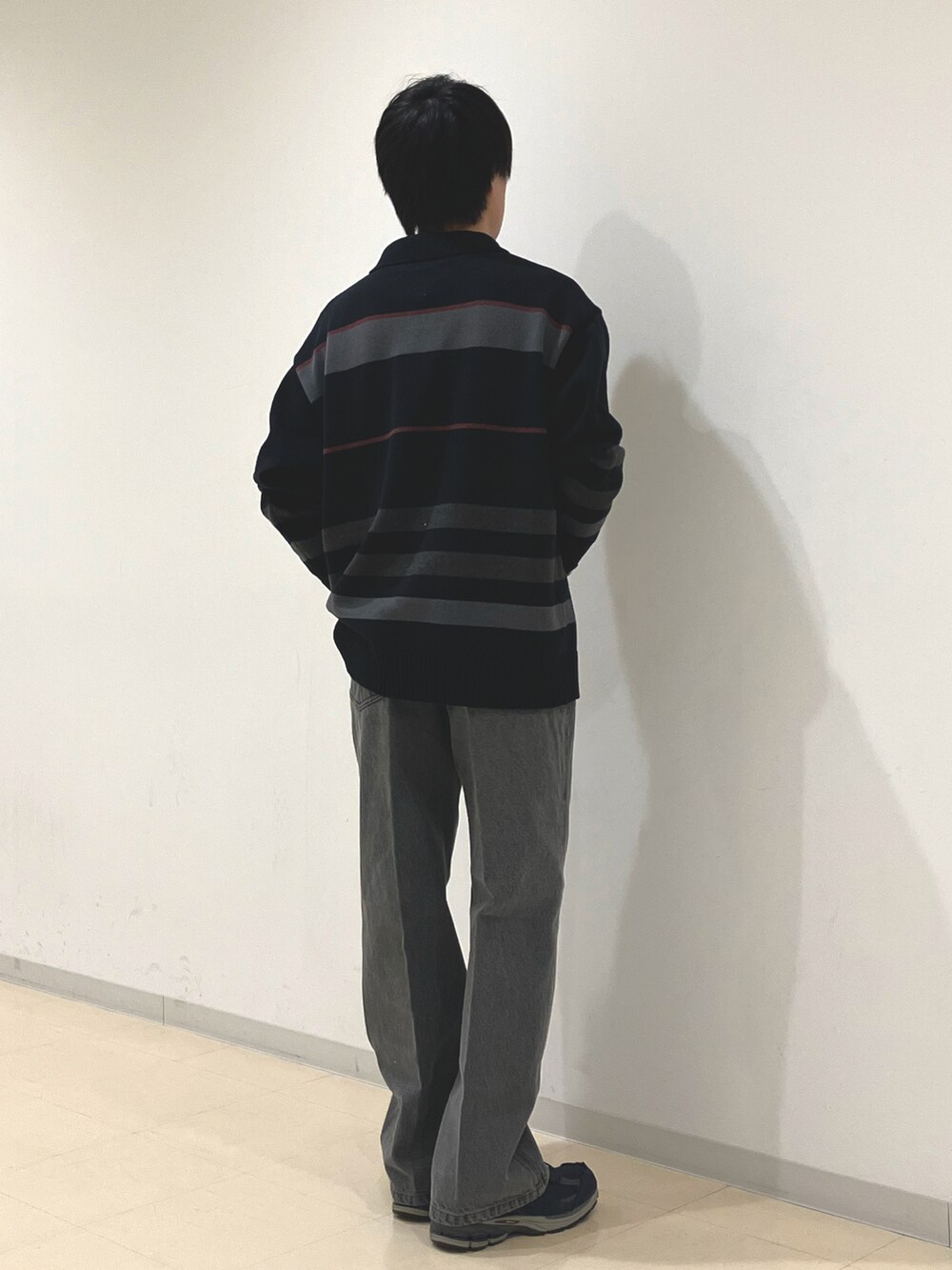 ブラック系のニット/セーター、ブラック系のデニムパンツ、ブルー系のスニーカーを着用したメンズの秋コーディネートの3枚目の写真