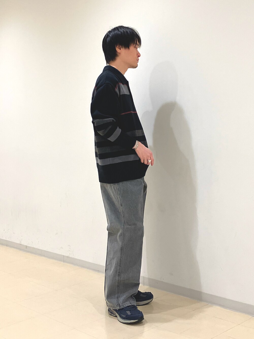 ブラック系のニット/セーター、ブラック系のデニムパンツ、ブルー系のスニーカーを着用したメンズの秋コーディネートの2枚目の写真