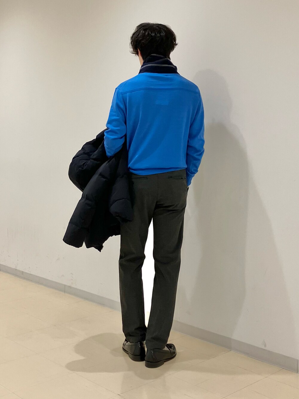 ブルー系のニット/セーター、ブラック系のダウンジャケット/コート、グレー系のその他パンツを着用したメンズの冬コーディネートの3枚目の写真