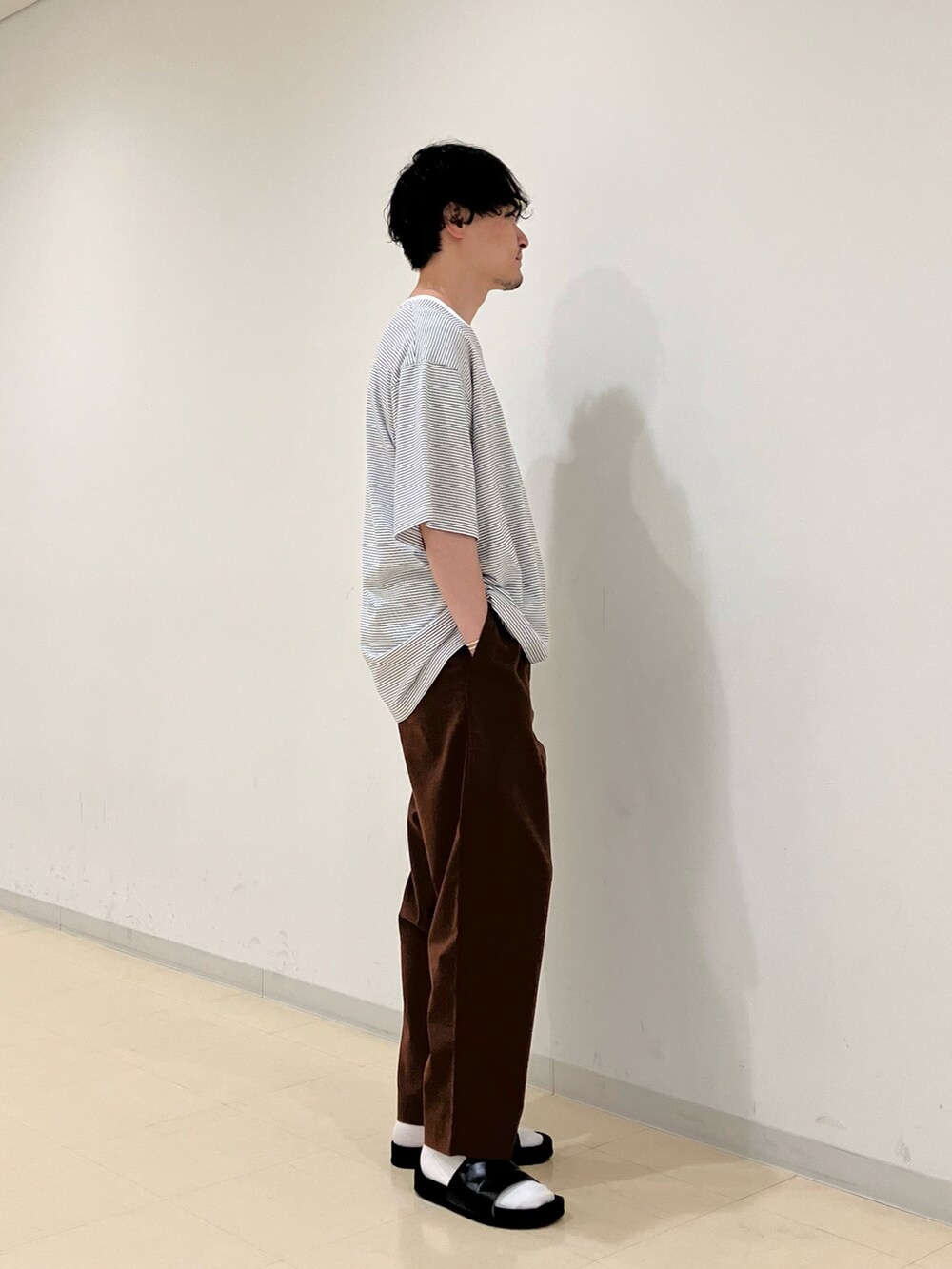 ホワイト系のTシャツ/カットソー、ブラウン系のその他パンツ、ブラック系のサンダルを着用したメンズの夏コーディネートの2枚目の写真