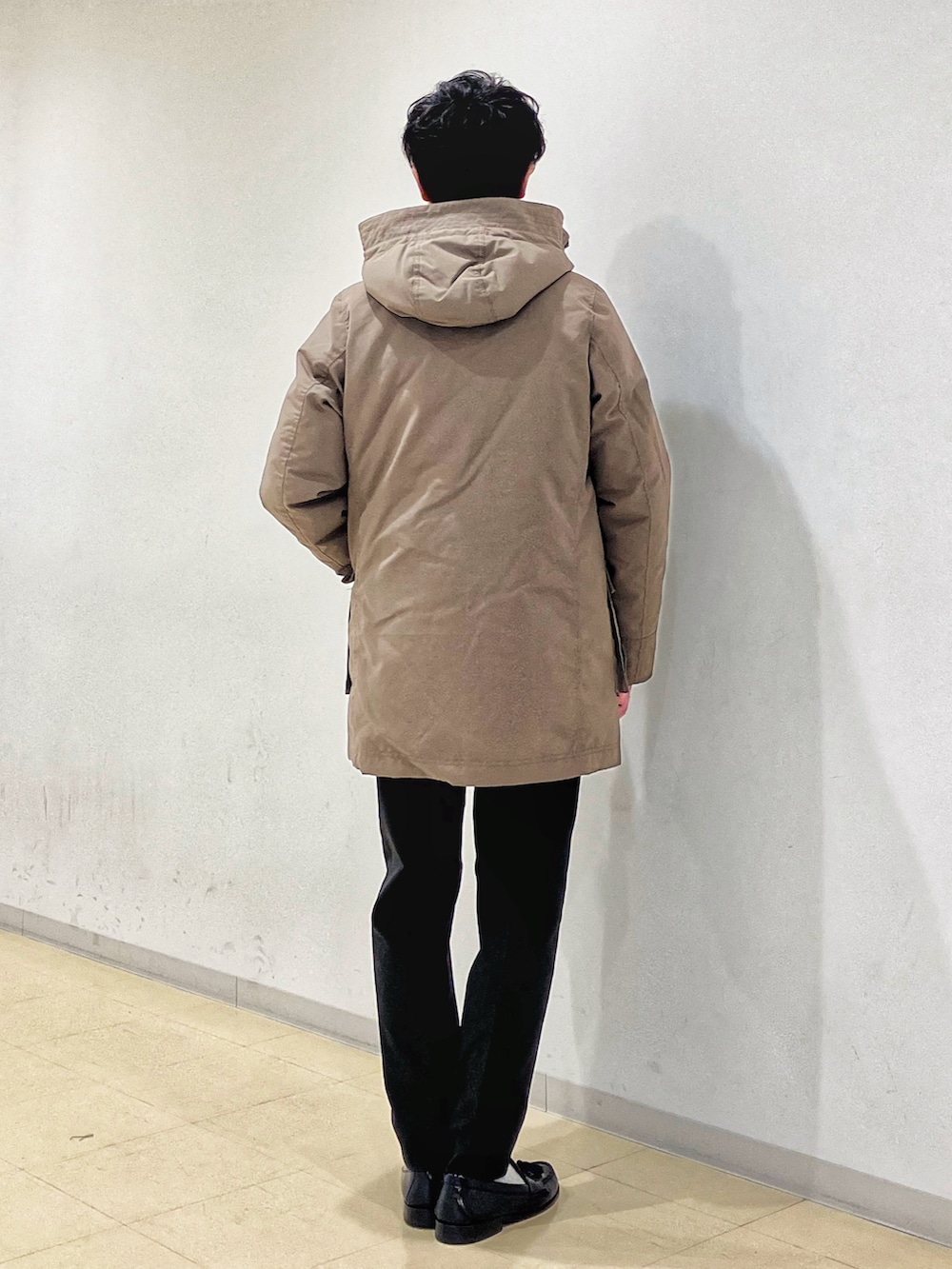 ブラウン系のダウンジャケット/コート、グレー系のセットアップ、ブラック系のニット/セーターを着用したメンズの冬コーディネートの4枚目の写真