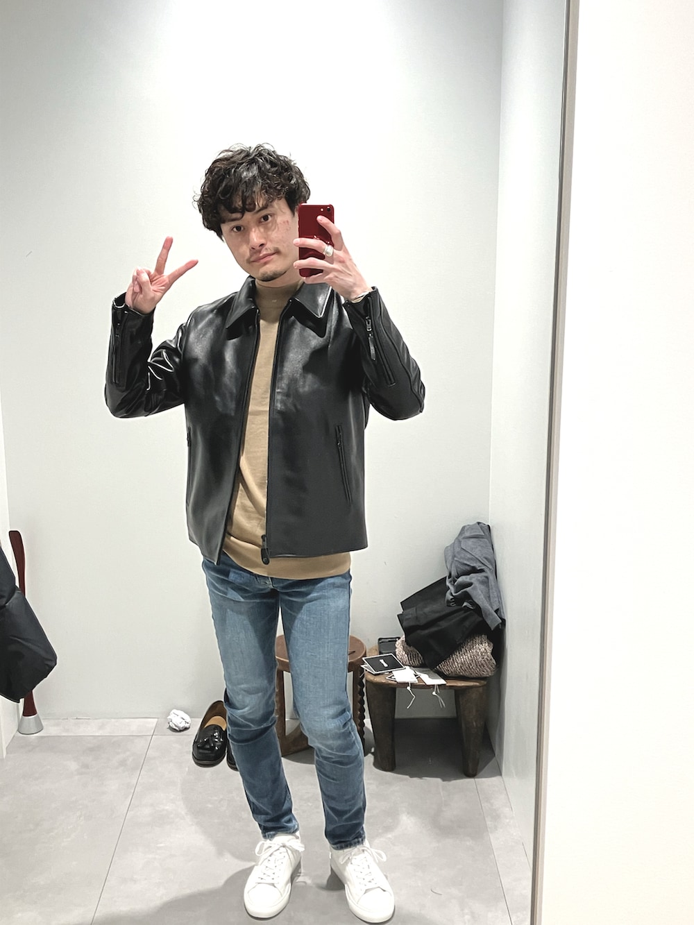 ブラック系のライダースジャケット、ベージュ系のニット/セーター、ブルー系のデニムパンツを着用したメンズの冬コーディネートの4枚目の写真