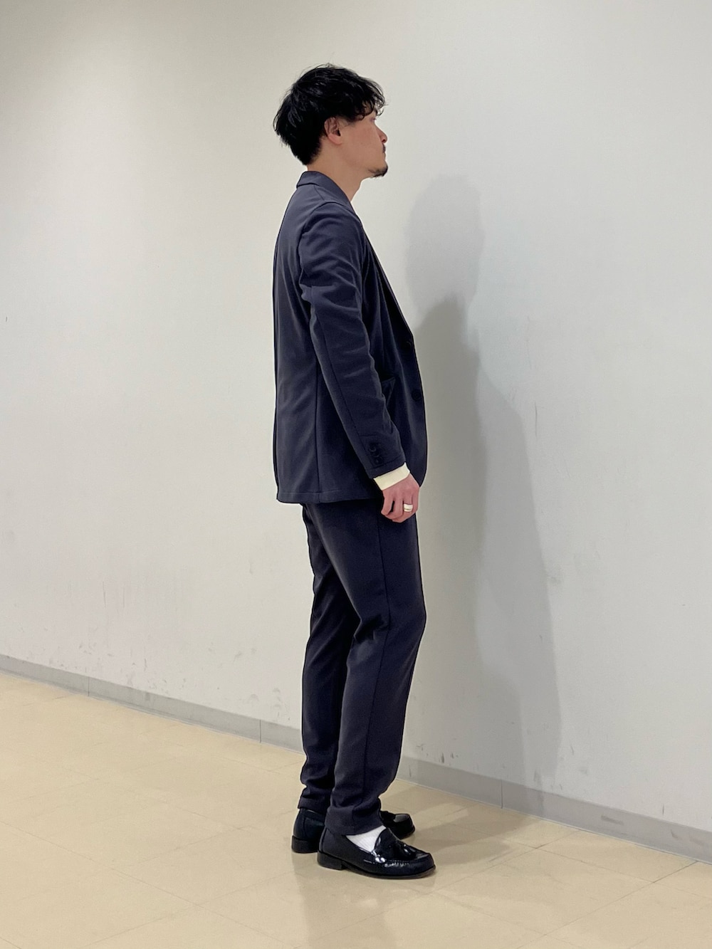 ベージュ系のニット/セーター、グレー系のスーツジャケット、グレー系のスーツパンツを着用したメンズの冬コーディネートの2枚目の写真