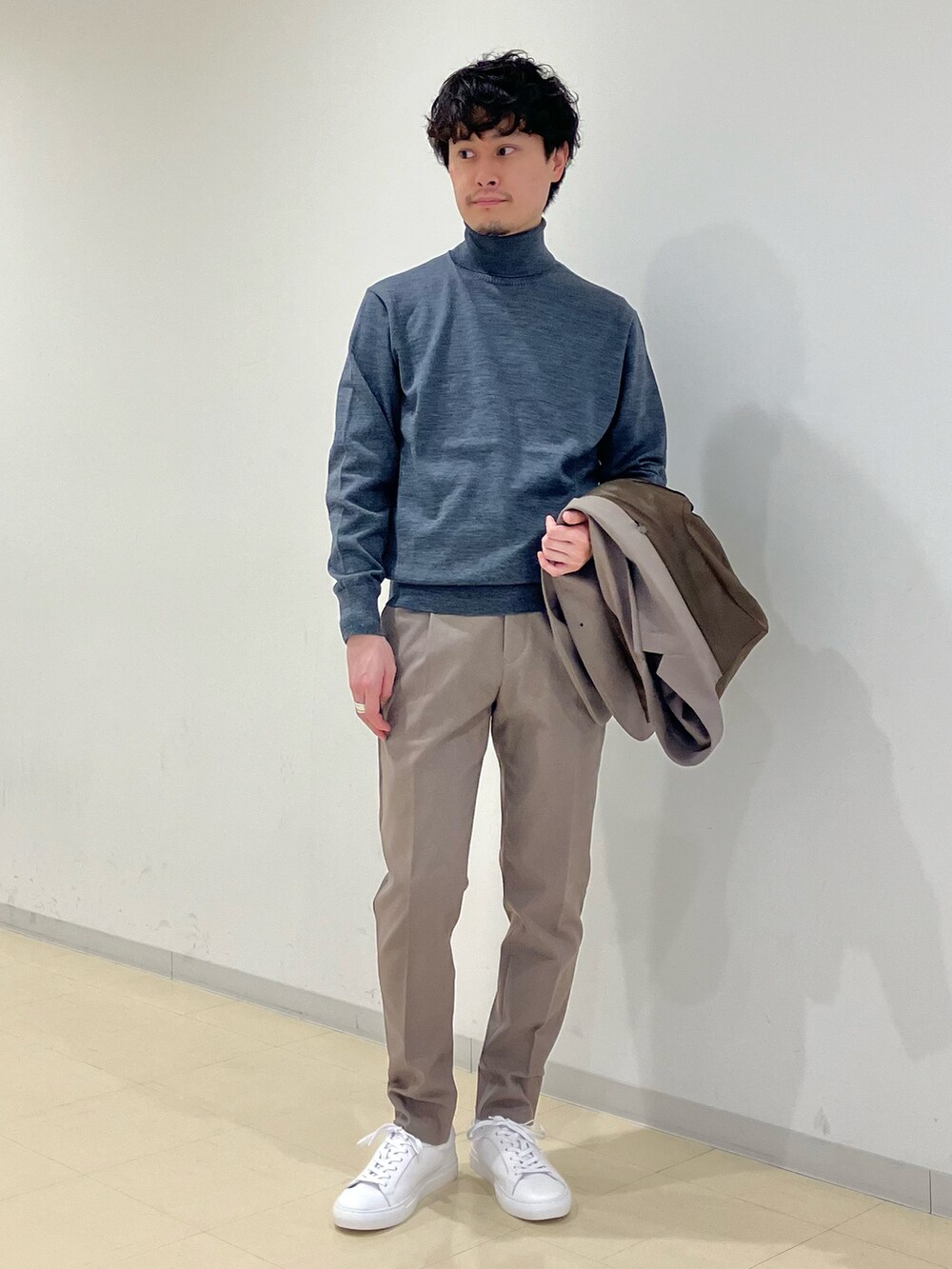 グレー系のニット/セーター、ブラック系のダウンジャケット/コート、ベージュ系のセットアップを着用したメンズの冬コーディネートの5枚目の写真