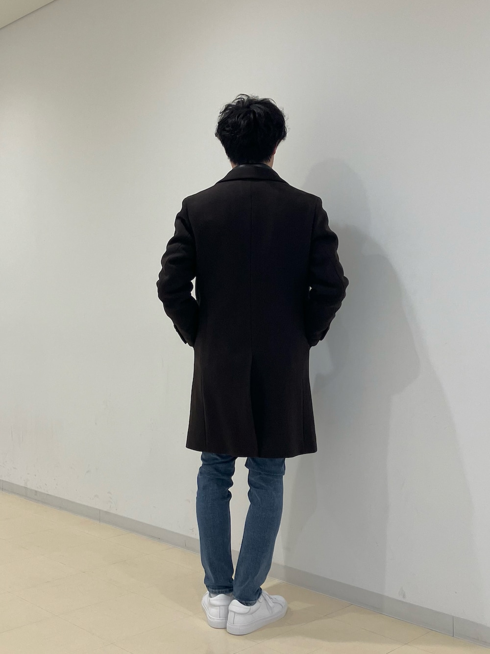 ブラウン系のチェスターコート、ブラック系のライダースジャケット、ブルー系のデニムパンツを着用したメンズの冬コーディネートの4枚目の写真