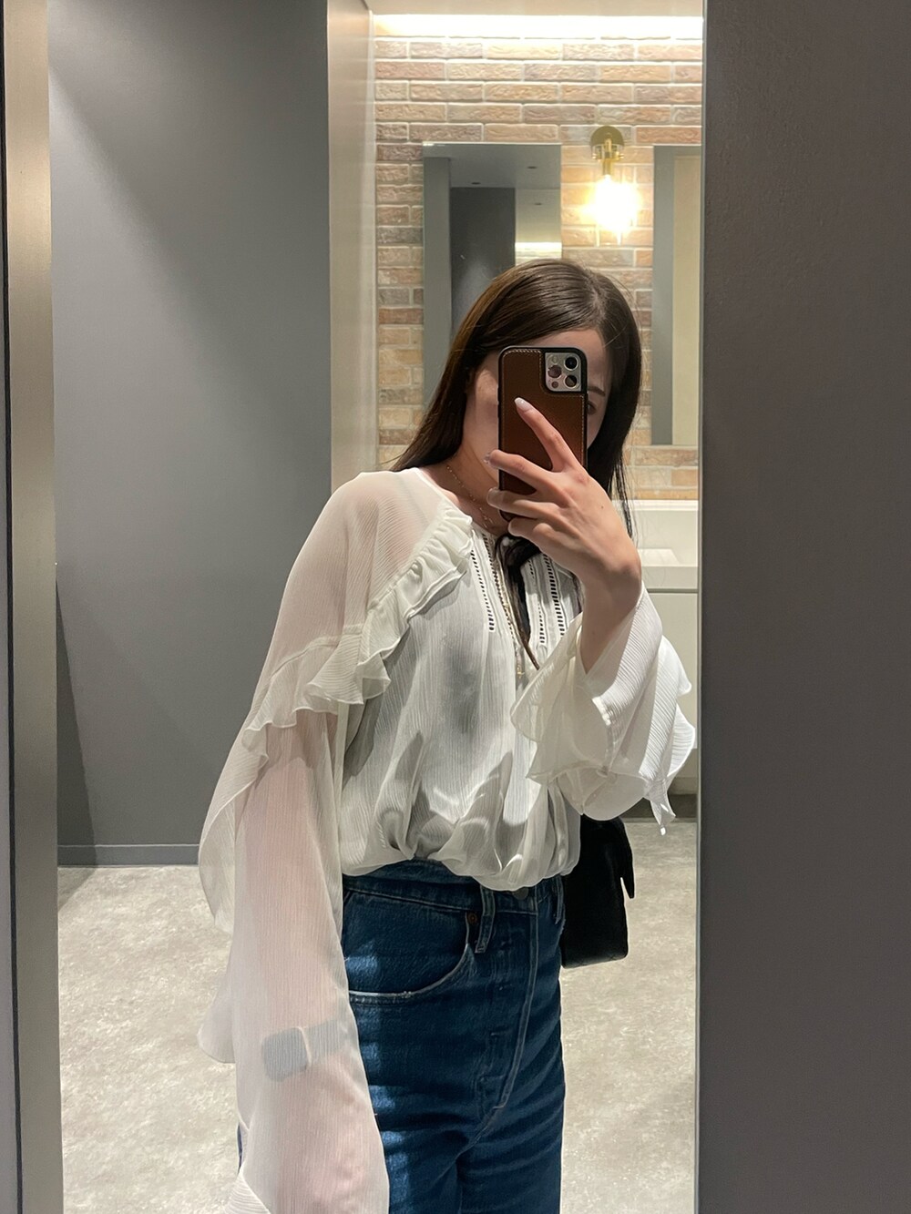 ブルー系のデニムパンツ、ホワイト系のシャツ/ブラウス、ブラック系のショルダーバッグを着用したレディースの秋コーディネートの2枚目の写真