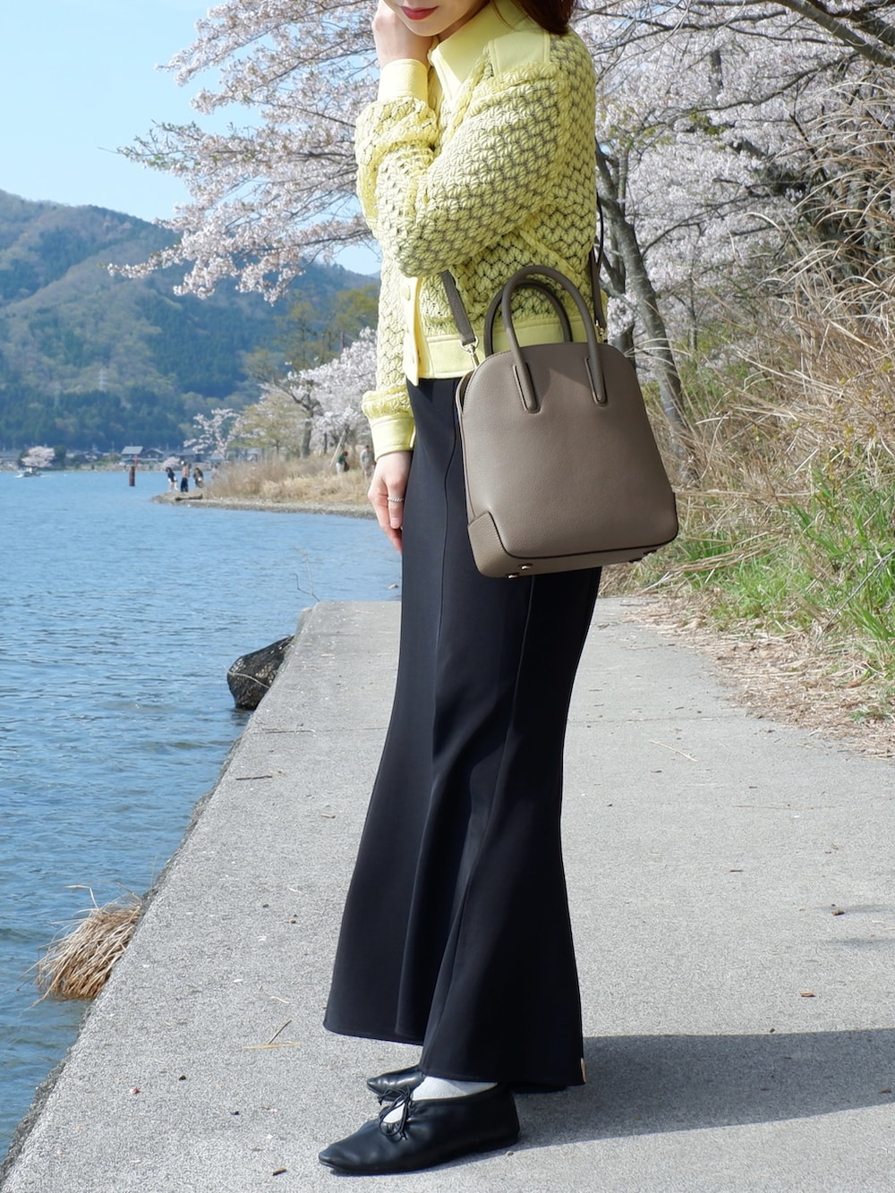 ブラウン系のショルダーバッグ、ブラック系のパンプス、イエロー系のシャツ/ブラウスを着用したレディースの春コーディネートの2枚目の写真