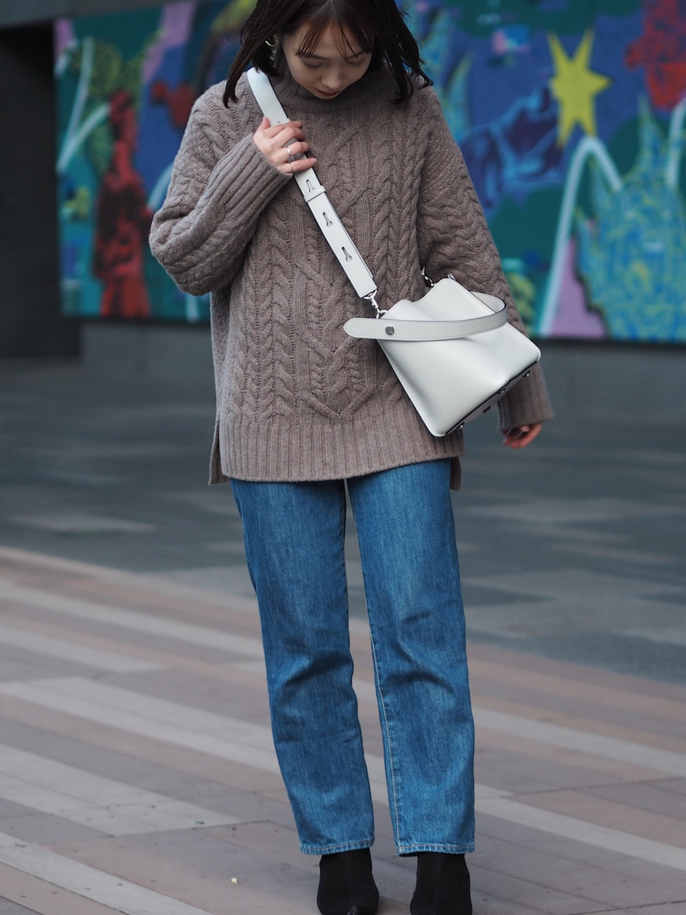 ブルー系のデニムパンツ、ブラック系のブーツ、グレー系のショルダーバッグを着用したレディースの冬コーディネートの3枚目の写真