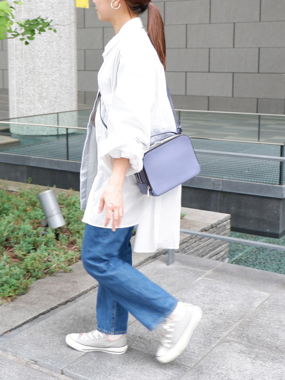 ブルー系のデニムパンツ、グレー系のスニーカー、パープル系のショルダーバッグを着用したレディースの夏コーディネートの4枚目の写真