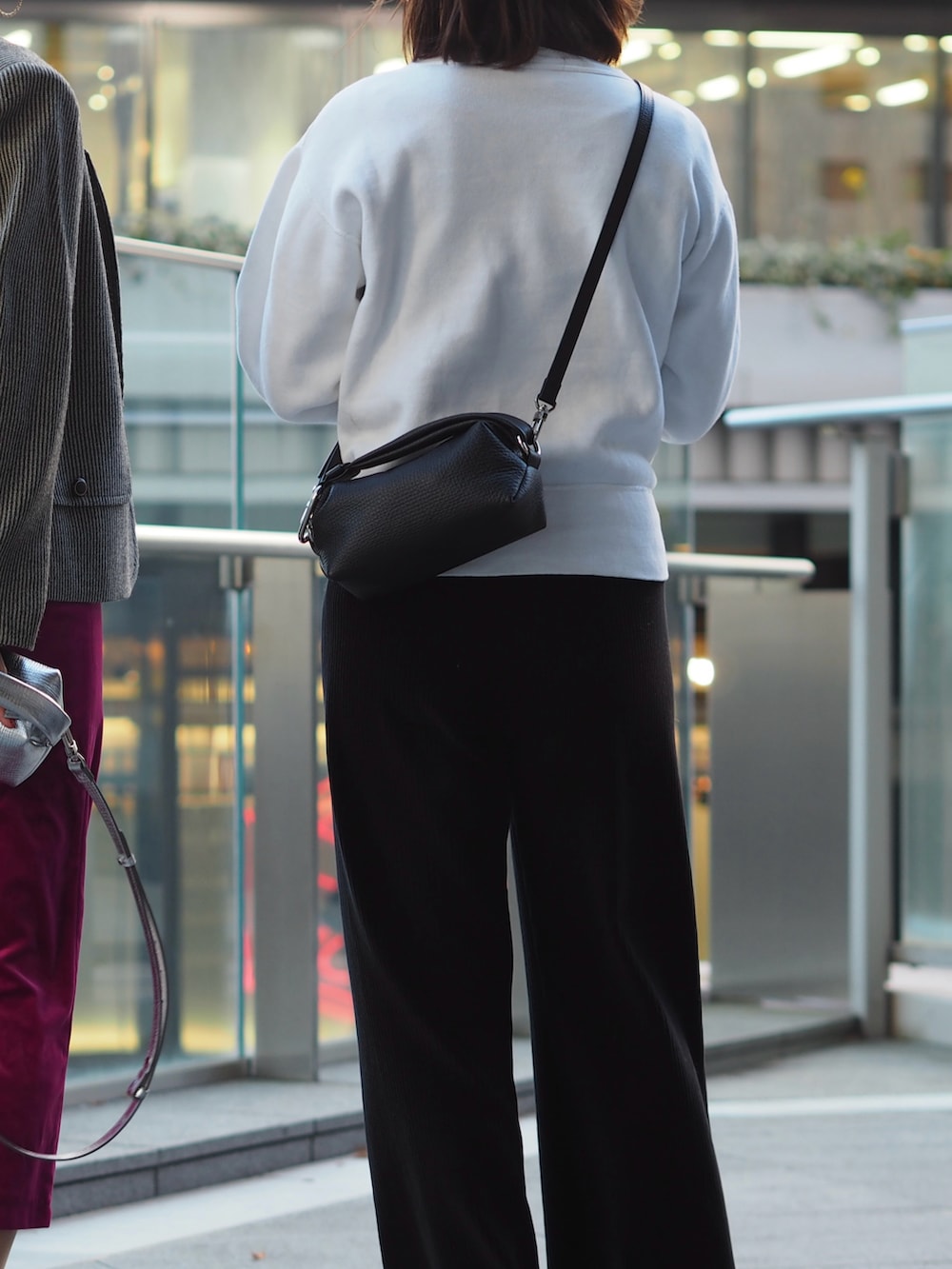 ホワイト系のスウェット、ブラック系のスニーカー、ブラック系のクラッチバッグを着用したレディースの冬コーディネートの2枚目の写真