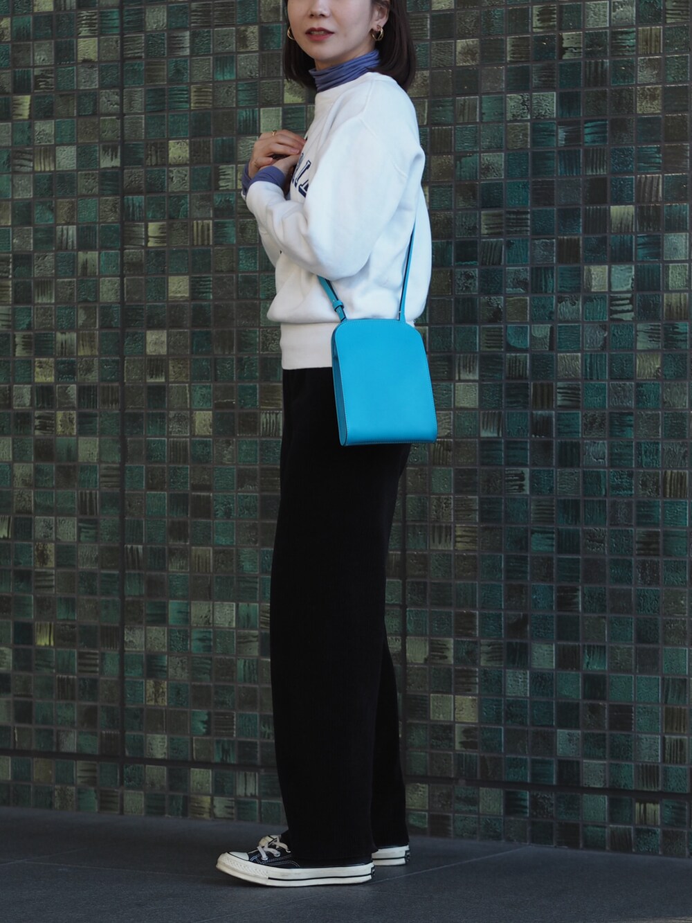 ブラック系のスニーカー、ブルー系のショルダーバッグ、ホワイト系のスウェットを着用したレディースの冬コーディネートの2枚目の写真