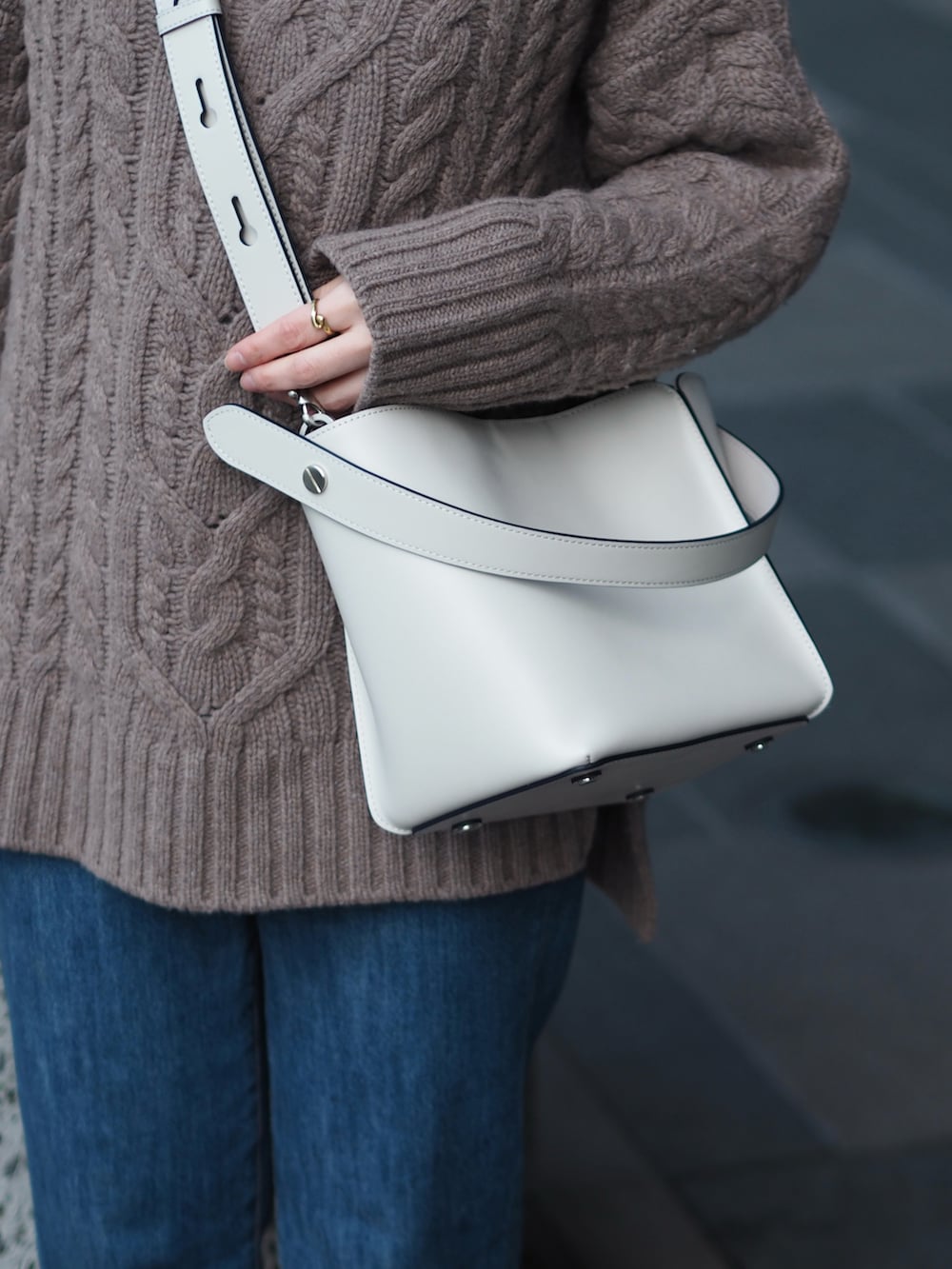 ブルー系のデニムパンツ、ブラック系のブーツ、グレー系のショルダーバッグを着用したレディースの冬コーディネートの4枚目の写真