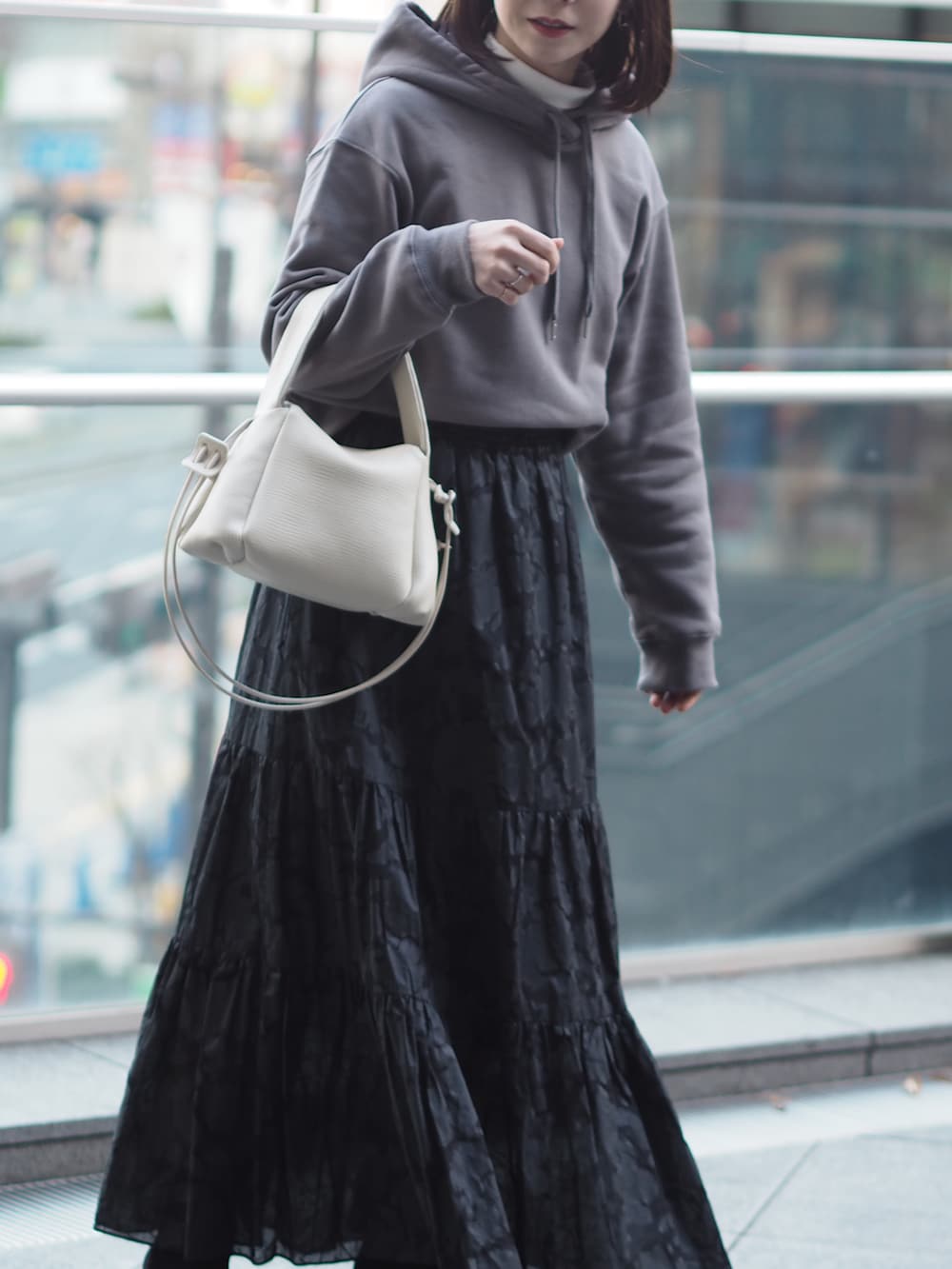 ホワイト系のショルダーバッグ、グレー系のスウェット、ブラック系のスカートを着用したレディースの冬コーディネートの5枚目の写真