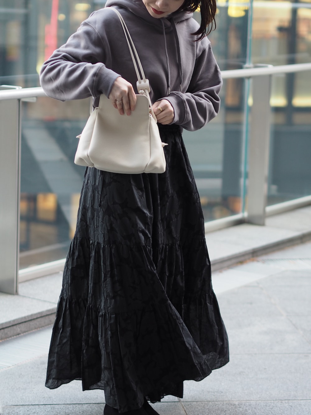 ホワイト系のショルダーバッグ、グレー系のスウェット、ブラック系のスカートを着用したレディースの冬コーディネートの3枚目の写真