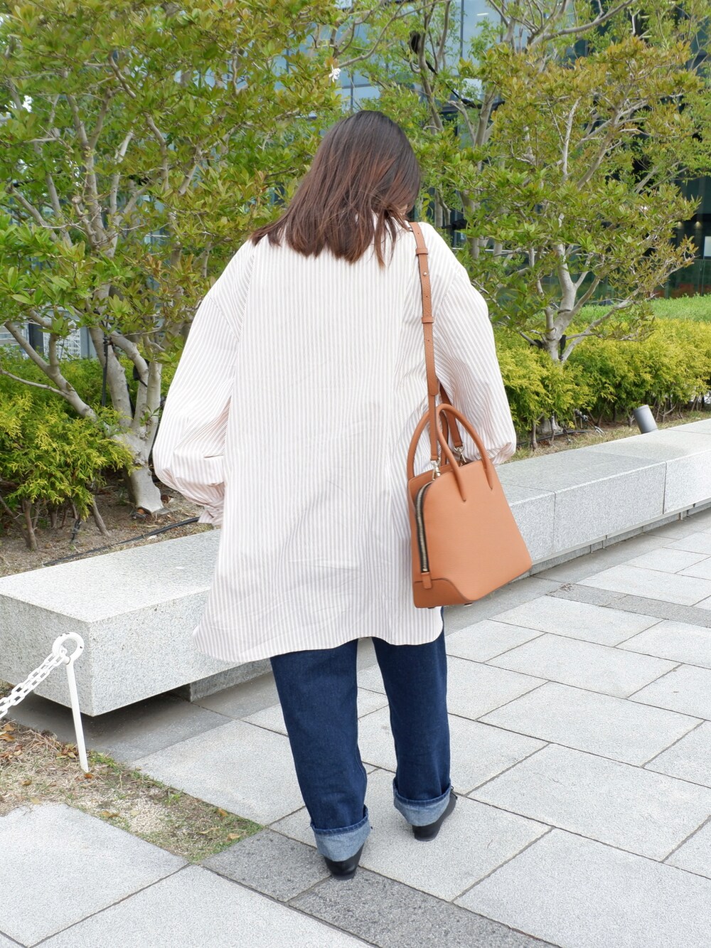 ブラック系のパンプス、ブルー系のデニムパンツ、ブラウン系のボストンバッグを着用したレディースの春コーディネートの3枚目の写真