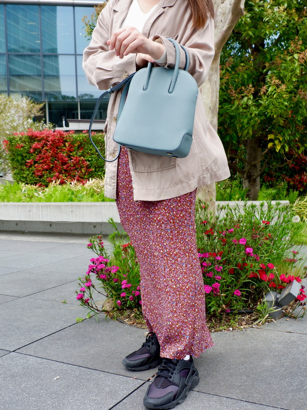 ブルー系のショルダーバッグ、レッド系のスカート、ホワイト系のスニーカーを着用したレディースの春コーディネートの2枚目の写真