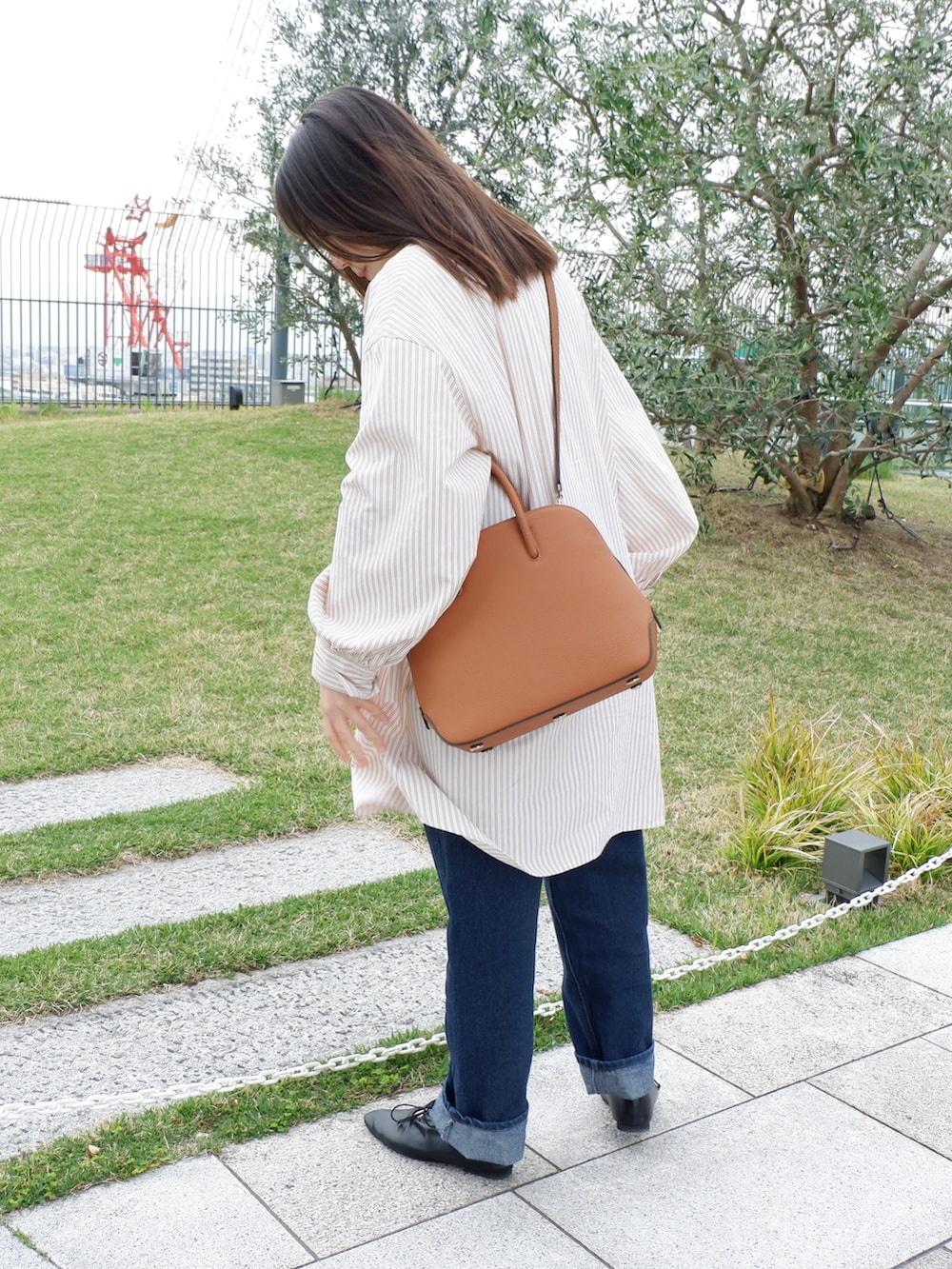 ブラック系のパンプス、ブルー系のデニムパンツ、ブラウン系のボストンバッグを着用したレディースの春コーディネートの2枚目の写真